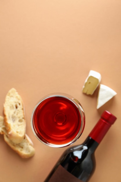 Bouteille et verre de vin, fromage et pain sur fond beige