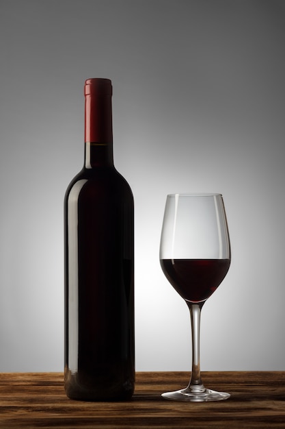 Bouteille et verre de vin rouge avec un léger dégradé sur le fond