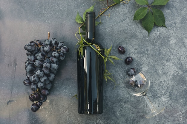 Bouteille de verre à vin de vigne verte de vin rouge et de raisin mûr sur le dessus de fond de table en pierre sombre vintage vi...