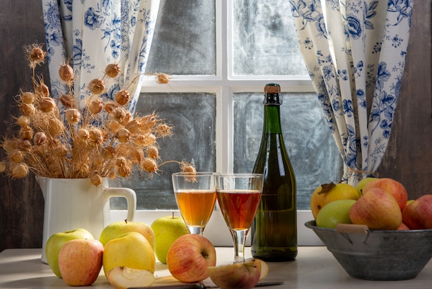 Bouteille et verres de cidre aux pommes. Dans une maison rustique, fond de fenêtre