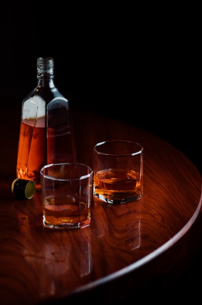 Une bouteille et des verres de liqueur sur une table en bois