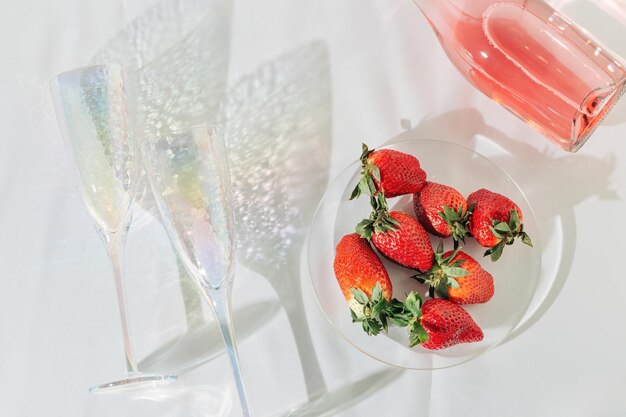 Bouteille de verres transparents avec vin mousseux rose et fraise de fruits rouges