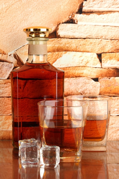 Bouteille et verres de whisky et de glace sur fond de mur de briques