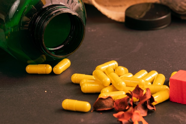 Bouteille verte de suppléments avec capsules jaunes sur fond noir