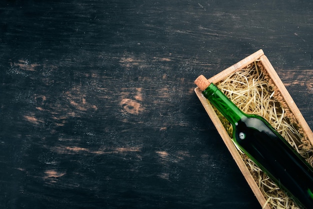 Une bouteille de vieux vin rouge dans une boîte Sur un fond en bois noir Vue de dessus Copiez l'espace pour votre texte