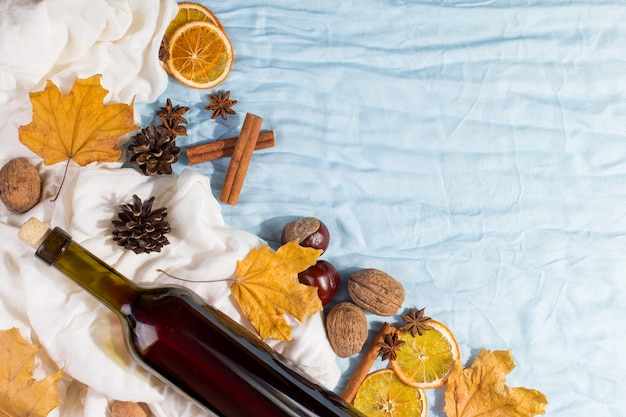 Une bouteille de vin chaud avec des épices, un foulard, des feuilles sèches et des oranges sur une table. Humeur d'automne, une méthode pour garder au chaud dans le froid, la surface.