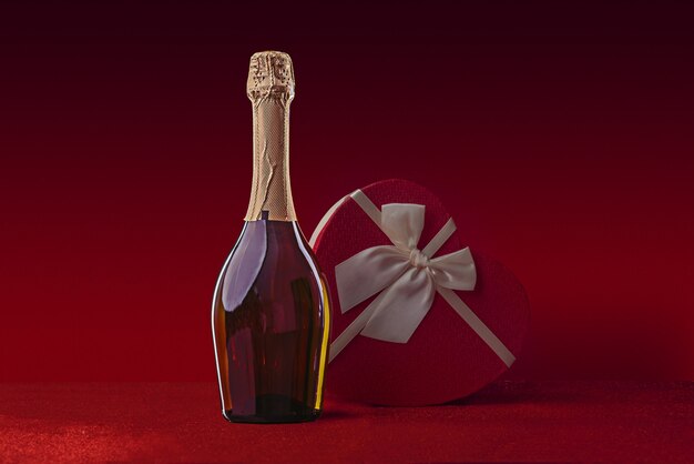 Photo bouteille de vin et coffret cadeau en forme de coeur avec un noeud sur un paillettes