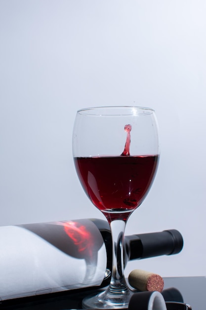 Une bouteille de vin et des gouttes dégoulinant dans un verre