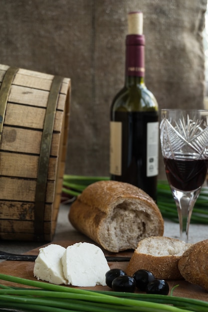 Bouteille de vin, olives, fromage et pain sont en sac