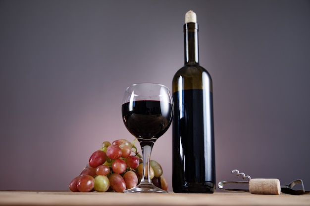 Bouteille de vin de raisins et verre avec ouvre-table sur table