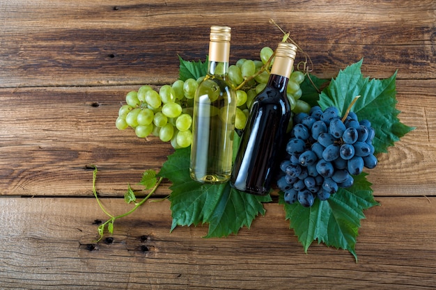 Une bouteille de vin rouge et blanc avec des raisins sur un fond en bois