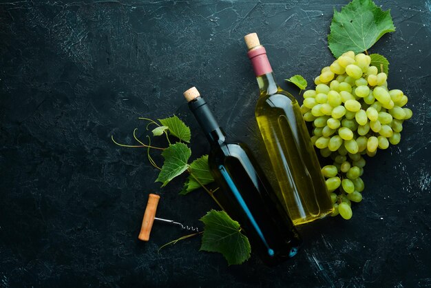 Bouteille de vin rouge et blanc et de raisins sur une table en pierre noire Vue de dessus Espace libre pour votre texte