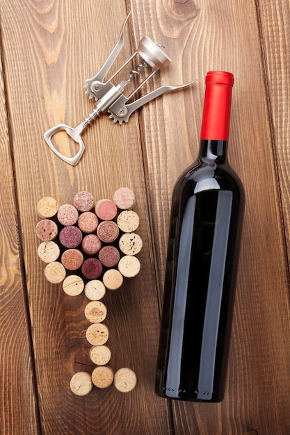 Bouteille de vin rouge, bouchons en verre et tire-bouchon. Vue d'en haut sur fond de table en bois rustique