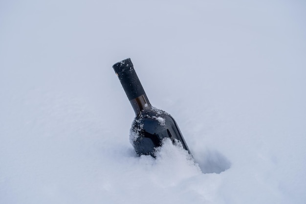 Bouteille de vin rouge sur un lit de neige et fond blanc