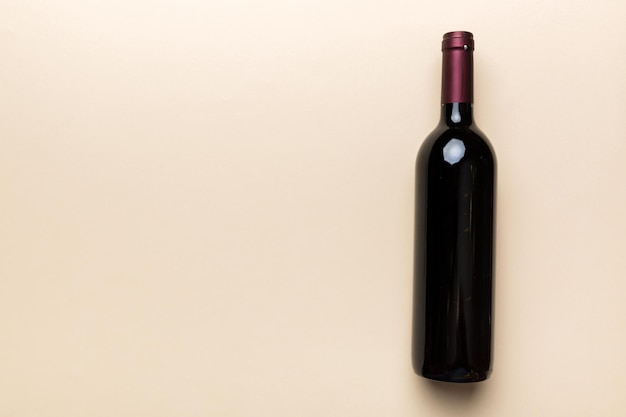Une bouteille de vin rouge sur une table colorée. Mise à plat, vue de dessus avec espace de copie.