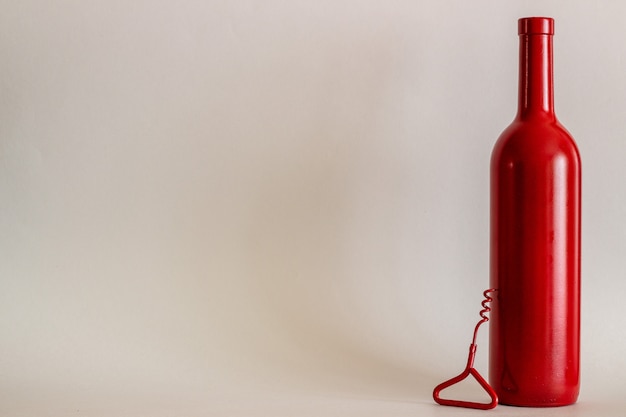 Photo bouteille de vin rouge et tire-bouchon. fond gris. minimalisme.