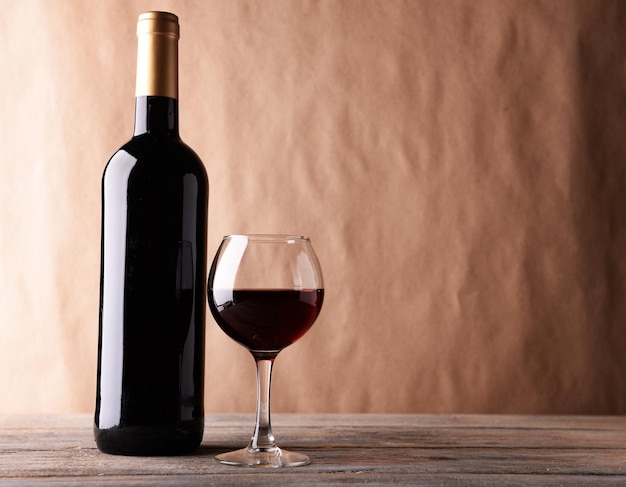 Une bouteille de vin rouge et un verre sur une table en bois
