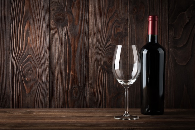 Bouteille de vin rouge et verre de vin sur le fond en bois foncé, lumière de studio