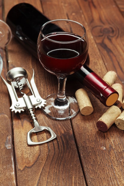Bouteille de vin rouge, verre à vin et tire-bouchon sur table en bois