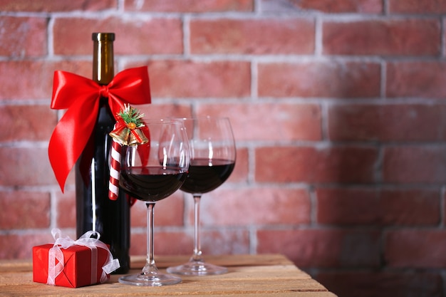 Bouteille de vin rouge et verres avec des cadeaux de Noël sur le mur