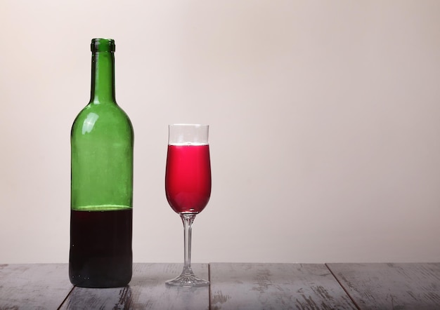 Bouteille de vin rouge et verres sur table en bois fond gris
