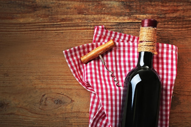 Bouteille de vin avec un tire-bouchon sur fond de bois