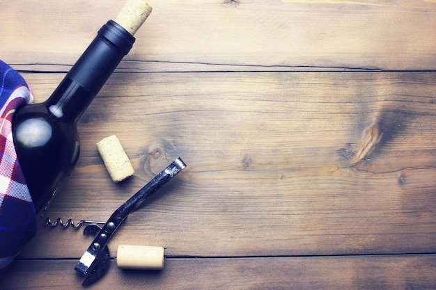 Bouteille de vin avec tire-bouchon isolé sur table en bois