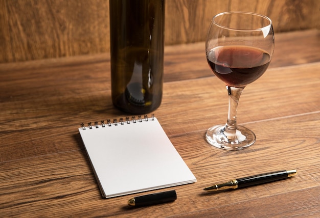 Bouteille de vin avec un verre et un bloc-notes