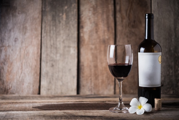 Bouteille de vin, verre et fleur blanche sur fond de bois