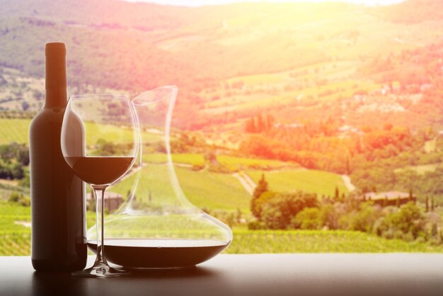 Photo bouteille de vin et de verre sur le fond des vignobles un jour ensoleillé