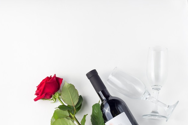 Bouteille de vin, verre et rose rouge avec des pétales sur fond blanc isolé