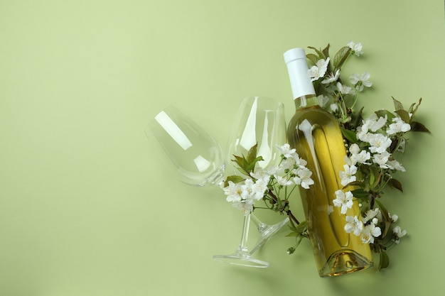 Bouteille de vin, verres et fleurs sur fond vert