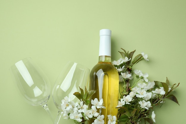 Bouteille de vin, verres et fleurs sur fond vert