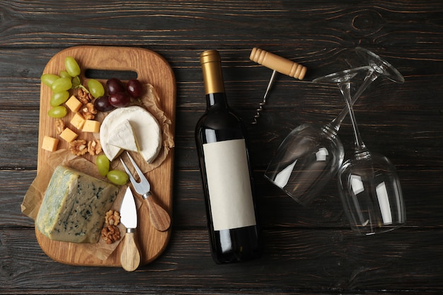 Bouteille de vin, verres, fromage et fruits sur bois