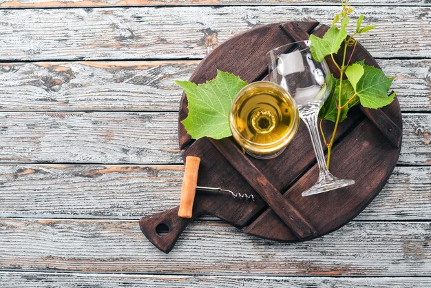 Une bouteille de vin avec des verres et des raisins Feuilles de raisin Vue de dessus Sur un fond en bois blanc Espace libre pour le texte