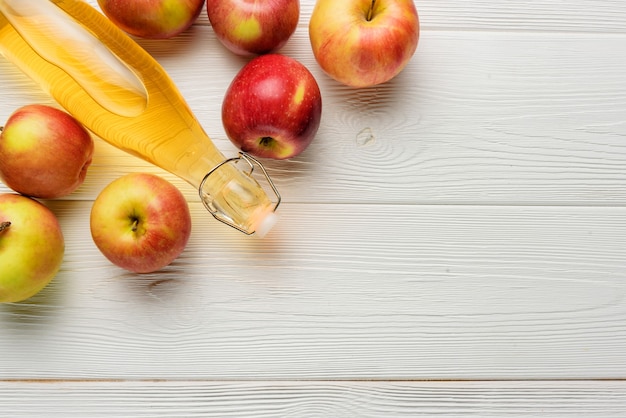 Une bouteille de vinaigre de cidre de pomme ou de jus de pomme sur fond blanc avec espace de copie. Composition à plat avec du cidre de pomme dans un gros plan de bouteille en verre.