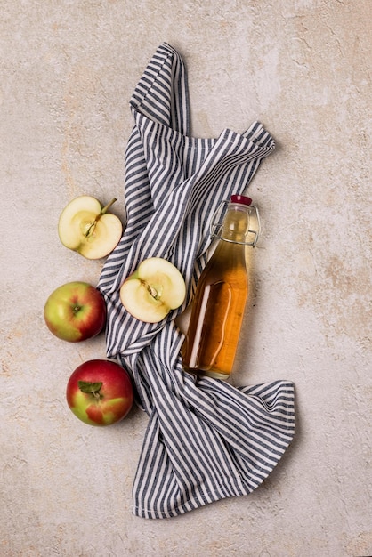 Bouteille de vinaigre de cidre de pomme ou de jus de pomme avec une serviette de pomme fraîche sur fond de béton Vue de dessus