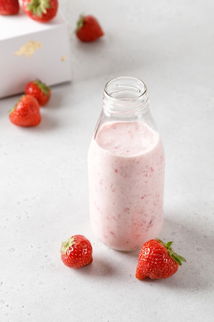 Bouteille de yaourt aux fraises ou de lait sur table grise et baies sur fond