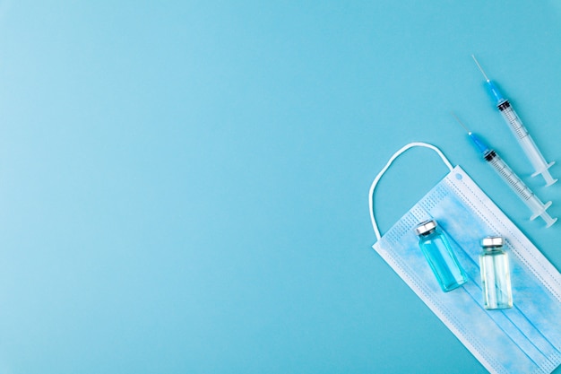 Photo bouteilles d'ampoules de vaccin en verre, seringues et aiguilles pilules sur fond bleu