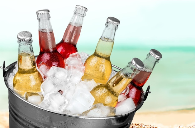 Bouteilles de bière dans la glace sur fond de plage