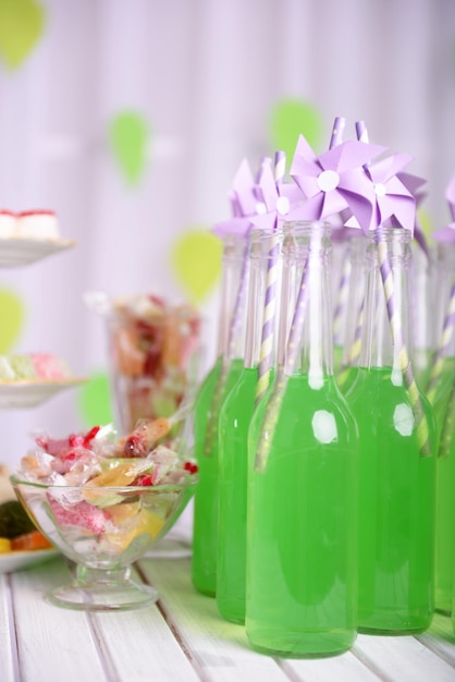 Bouteilles de boisson avec de la paille et des bonbons sur fond décoratif