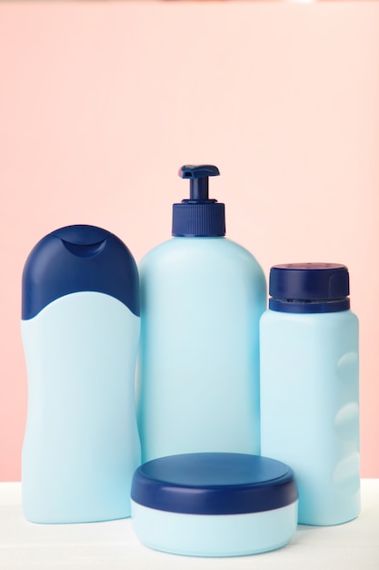 Bouteilles cosmétiques bleues sur rose