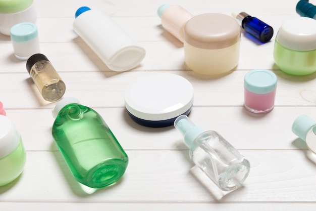 bouteilles cosmétiques, pots, conteneurs et sprays sur table en bois blanc