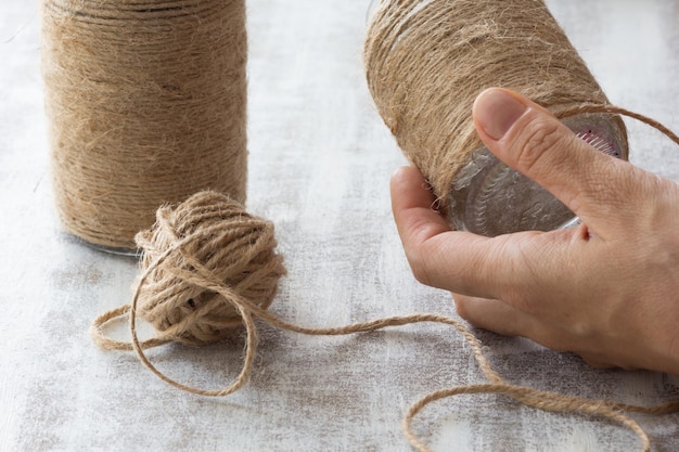 Bouteilles enveloppées de bricolage avec de la ficelle sur fond blanc