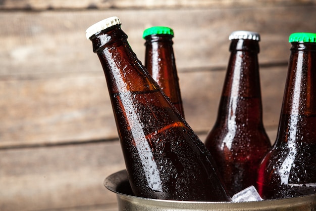 Bouteilles froides de bière dans le seau sur bois