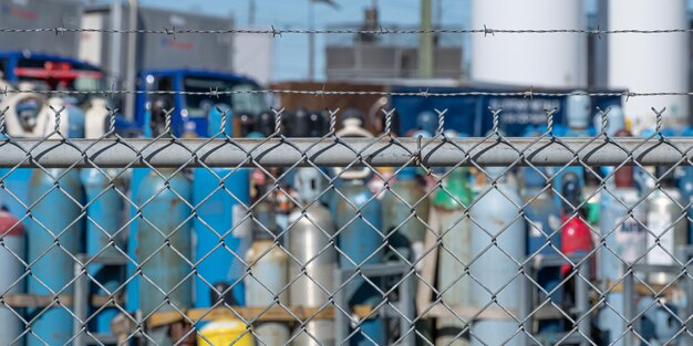 Bouteilles de gaz stockées derrière une clôture en treillis métallique en usine