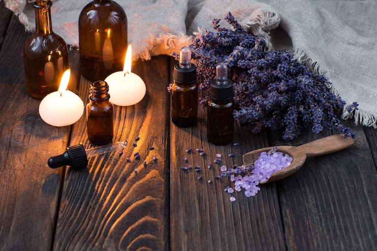 Photo bouteilles d'huile aromatique, bougies, sel de mer dans une cuillère en bois et fleurs de lavande