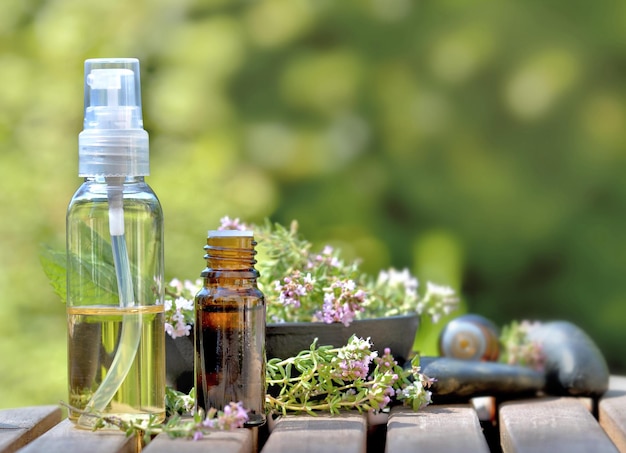 Bouteilles d'huile essentielle et fleurs d'herbe aromatique sur une table et sur fond vert