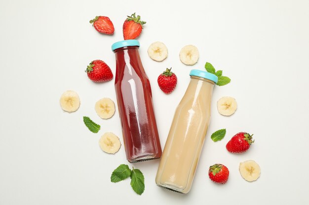 Bouteilles de jus de fraise et de banane sur blanc