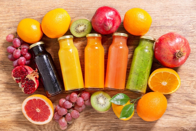 Bouteilles de jus de fruits avec des fruits frais sur une table en bois